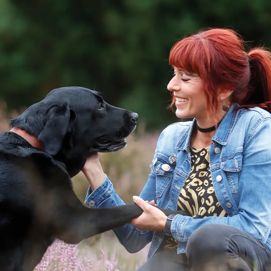 Anita mit schwarzem Labrador auf Wiese